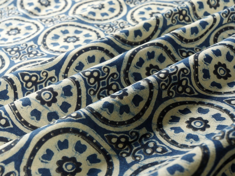 K&ouml;nnte beinhalten: Blauer und wei&szlig;er Stoff mit einem sich wiederholenden Muster aus stilisierten floralen Motiven. Der Stoff hat eine strukturierte, handgewebte Optik.