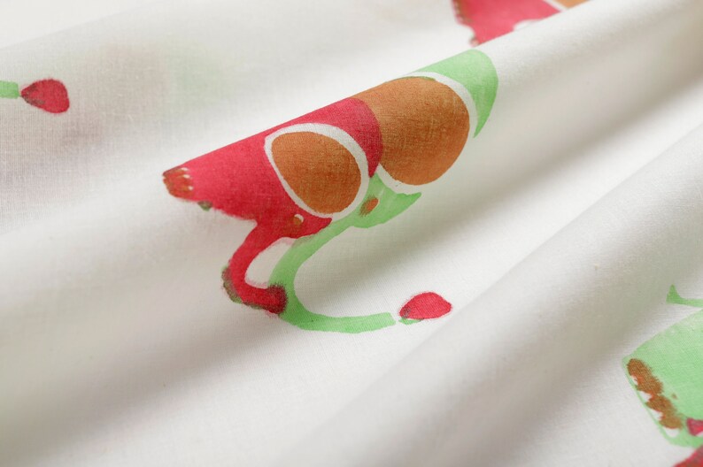 Puede incluir: Tela blanca con un patr&oacute;n repetido de formas abstractas rojas, naranjas y verdes. La tela tiene una textura suave y fluida.