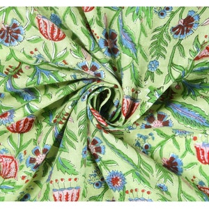Puede incluir: Una muestra de tela con un dise&ntilde;o floral. El dise&ntilde;o presenta flores rojas, azules y marrones con hojas y tallos verdes sobre un fondo verde claro. La tela est&aacute; recogida en un remolino.