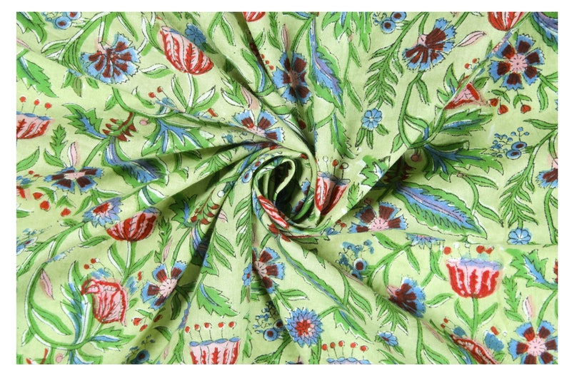 Puede incluir: Una muestra de tela con un dise&ntilde;o floral. El dise&ntilde;o presenta flores rojas, azules y marrones con hojas y tallos verdes sobre un fondo verde claro. La tela est&aacute; recogida en un remolino.