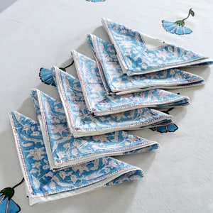 Pode incluir: Um conjunto de guardanapos de algod&atilde;o azul e branco com estampa floral. Os guardanapos s&atilde;o dobrados em forma triangular e t&ecirc;m uma borda branca.