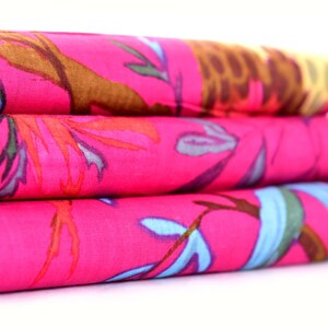 May include: A stack of three pink fabric squares with a colourful floral pattern. The fabric has a soft, flowing texture.