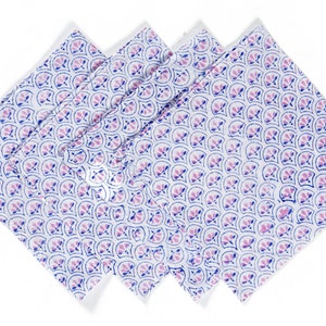 Puede incluir: Conjunto de cuatro servilletas de algodón blanco con un patrón floral rosa y azul. Las servilletas están dobladas y apiladas una encima de la otra.