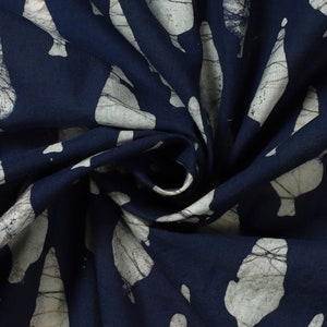 May include: A navy blue fabric with a white pattern of abstract shapes. The fabric is folded and twisted, showing the texture of the material.
