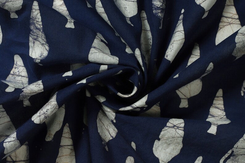 May include: A navy blue fabric with a white pattern of abstract shapes. The fabric is folded and twisted, showing the texture of the material.