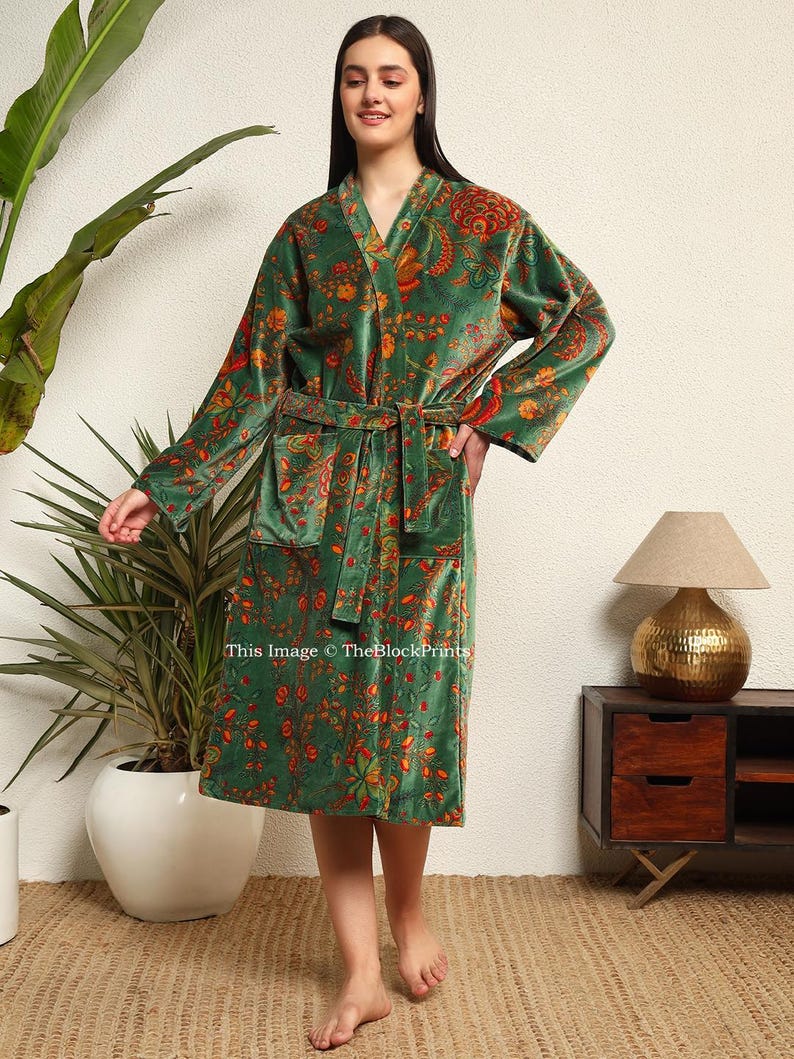May include: A green velvet robe with a floral print. The robe has a shawl collar, long sleeves, and a tie belt.
