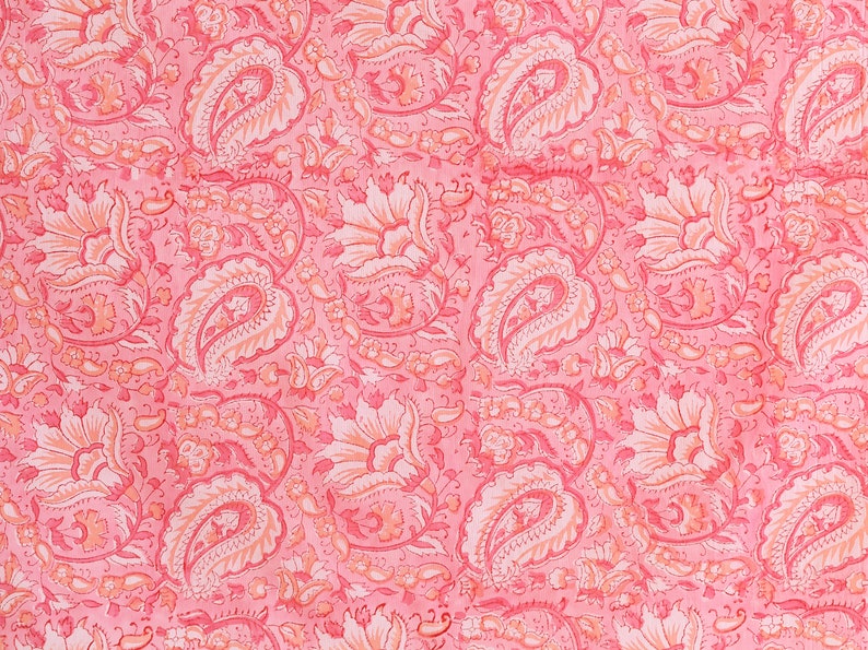 Puede incluir: Una tela rosa con un patr&oacute;n repetido de dise&ntilde;os paisley y florales blancos.
