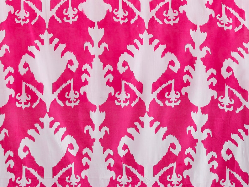 Op de afbeelding: Witte stof met een roze en wit ikat-patroon. Het patroon is een herhalend ontwerp van gestileerde bloemen.