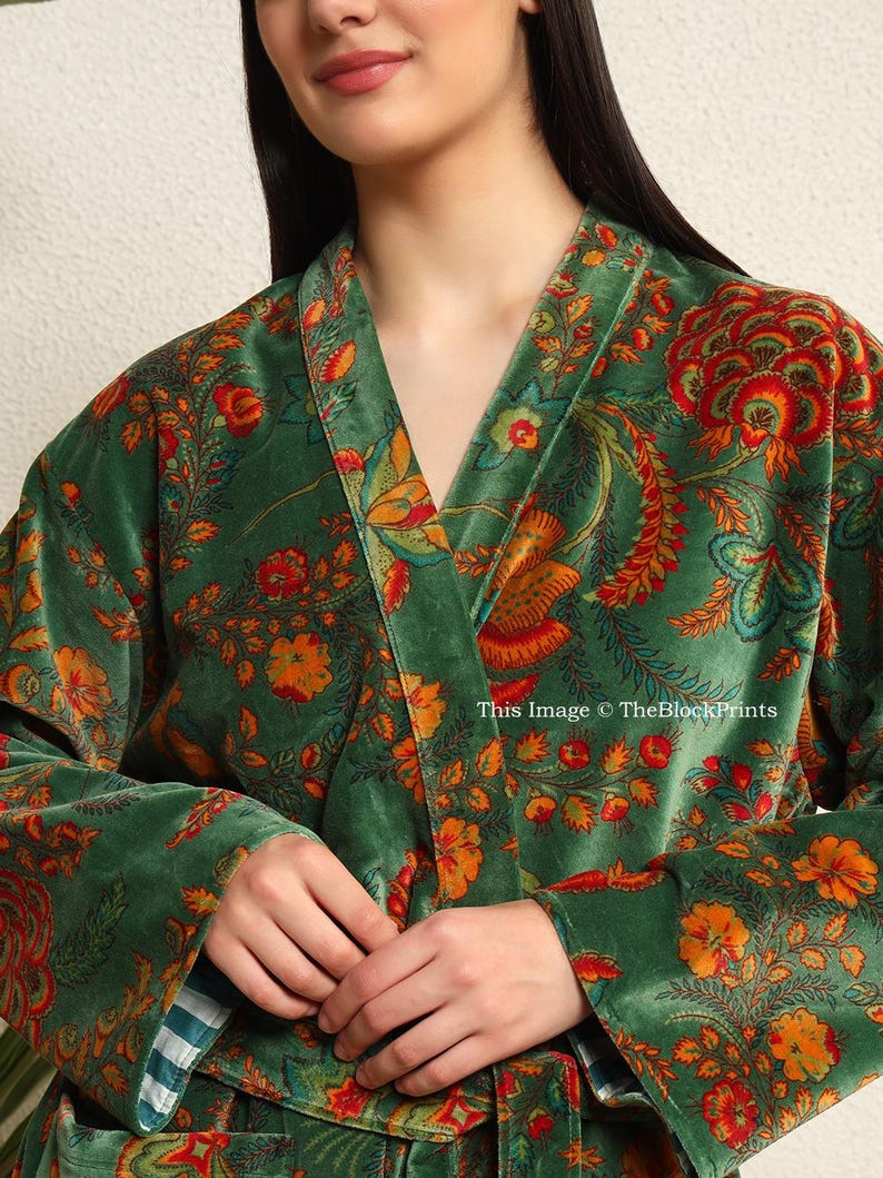 May include: A green velvet robe with a floral print in shades of orange, red, and yellow. The robe has a shawl collar and a tie belt.