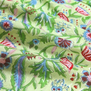 Puede incluir: Primer plano de una tela verde claro con un estampado floral. El dise&ntilde;o presenta flores rojas, azules y moradas con hojas y tallos verdes. La tela est&aacute; ligeramente arrugada, lo que sugiere que es un textil.