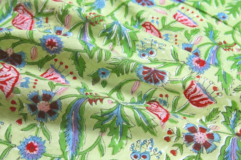 Puede incluir: Primer plano de una tela verde claro con un estampado floral. El dise&ntilde;o presenta flores rojas, azules y moradas con hojas y tallos verdes. La tela est&aacute; ligeramente arrugada, lo que sugiere que es un textil.