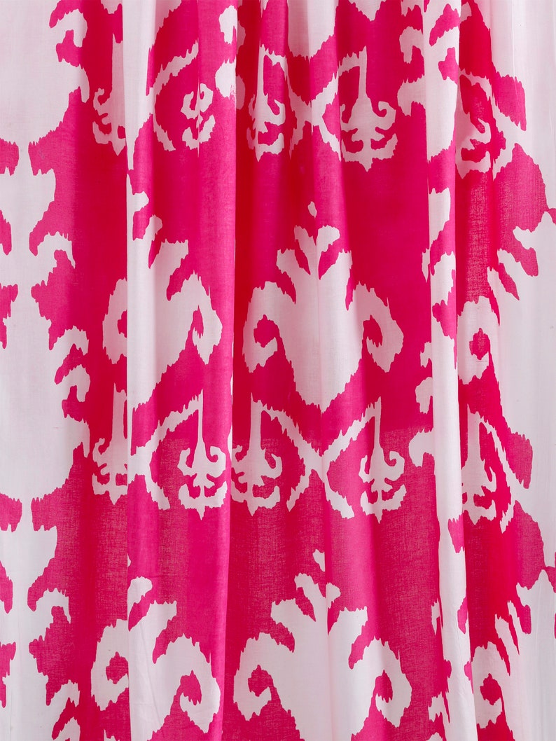 Op de afbeelding: Roze en witte stof met een herhalend patroon van gestileerde bloemmotieven. De stof heeft een zachte, vloeiende textuur.