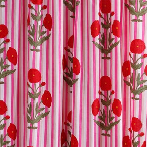 Op de afbeelding: Roze en witte gestreepte stof met een rood bloemenpatroon. De bloemen zijn gestileerd en lijken op klaprozen.