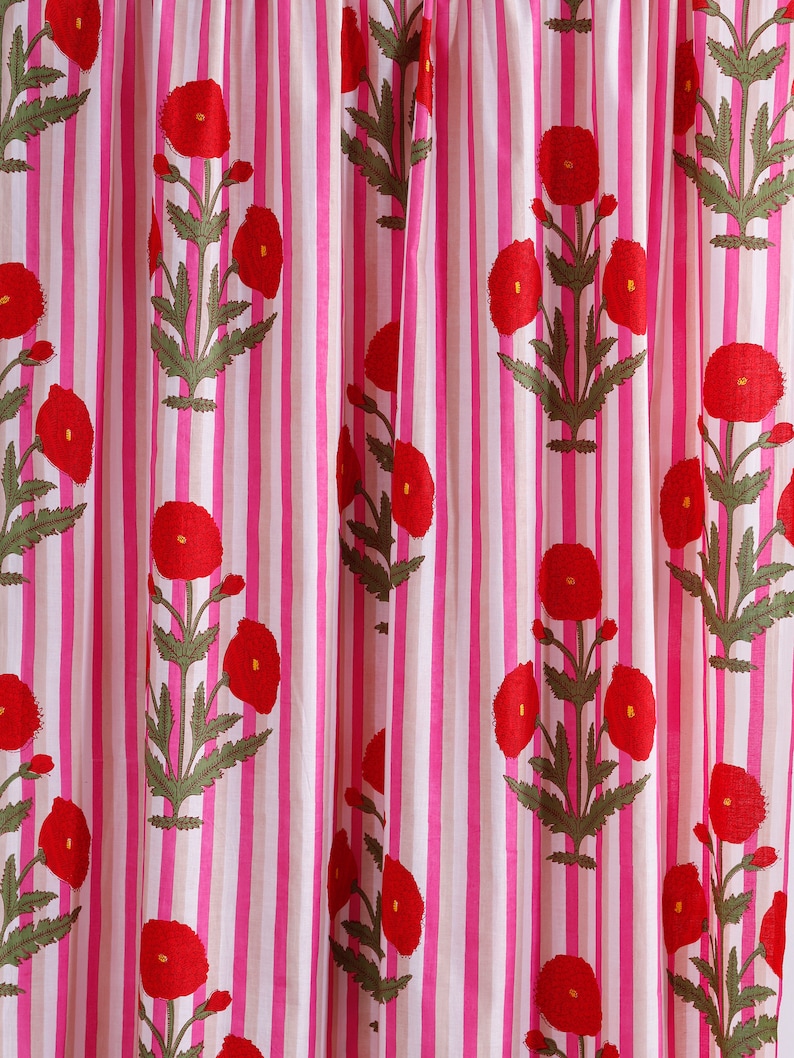 Op de afbeelding: Roze en witte gestreepte stof met een rood bloemenpatroon. De bloemen zijn gestileerd en lijken op klaprozen.