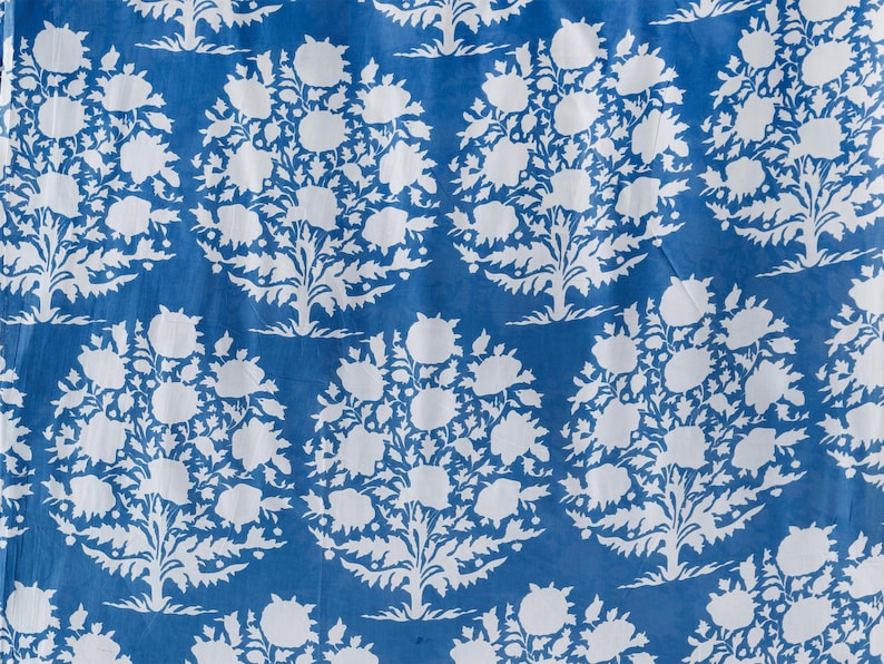 May include: A blue fabric with a white floral pattern. The pattern is a repeating design of stylised flowers and leaves.