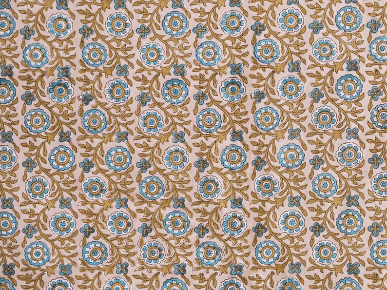 May include: A beige fabric with a repeating pattern of blue and brown floral designs. The fabric has a subtle texture and a soft, natural feel.