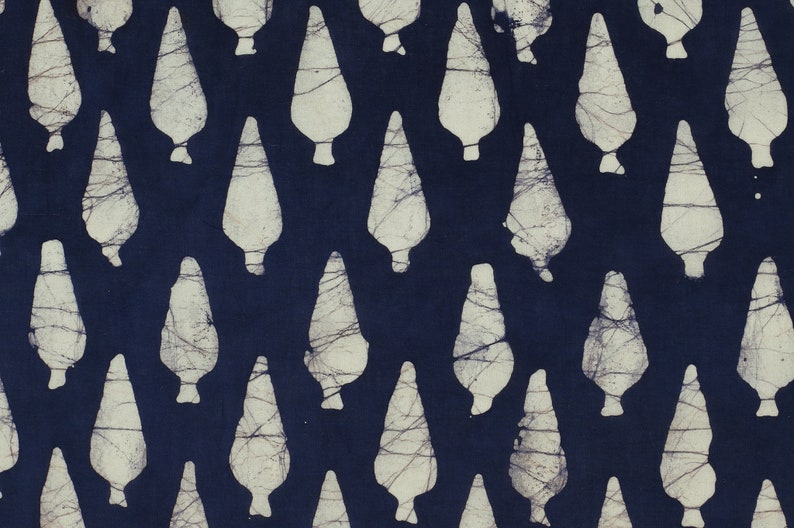 May include: A navy blue fabric with a white pattern of repeated teardrop shapes. The fabric has a batik style design.