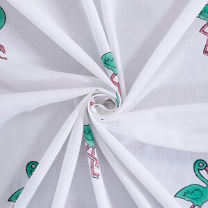 May include: White fabric with a repeating pattern of green flamingos with pink legs. The fabric is folded and twisted.