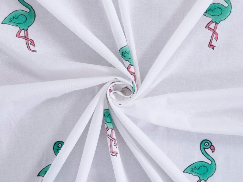 May include: White fabric with a repeating pattern of green flamingos with pink legs. The fabric is folded and twisted.