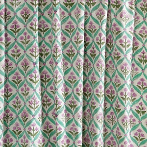May include: White fabric with a repeating pattern of green and purple floral designs. The pattern features a diamond shape with a floral motif in the center.