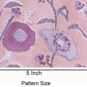 May include: A pink fabric with a floral pattern. The pattern features purple flowers with a white center and green leaves. The fabric is 5 inches wide and 3.5 inches tall.