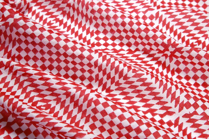 May include: Red and white checkered fabric with a subtle pattern. The fabric is folded and has a soft, textured surface.