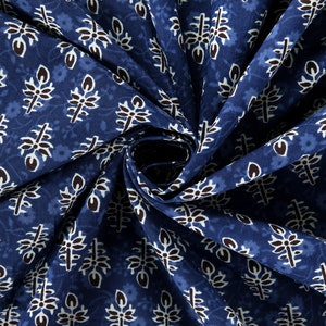 May include: Blue fabric with a white and black floral pattern. The fabric is folded in a spiral shape.