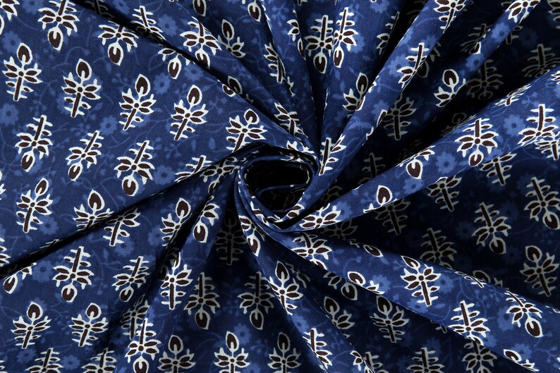 May include: Blue fabric with a white and black floral pattern. The fabric is folded in a spiral shape.