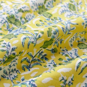 May include: Yellow fabric with a blue and green floral pattern. The fabric is folded and has a soft, textured surface.