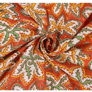 Pode incluir: Tecido vermelho com um padr&atilde;o floral branco, verde e amarelo. O tecido est&aacute; dobrado e tem uma superf&iacute;cie texturizada.