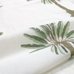 Peut inclure: Tissu blanc avec un motif r&eacute;p&eacute;t&eacute; de palmiers verts. Les palmiers ont des troncs bruns et des feuilles vertes.