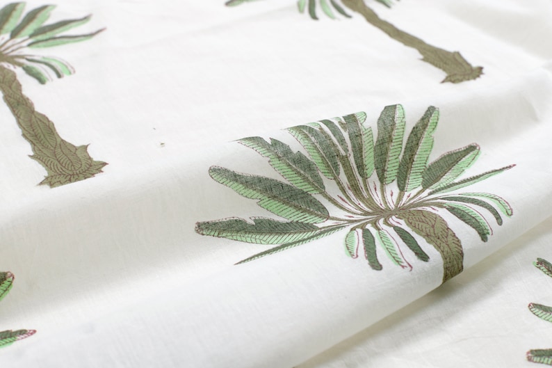 Peut inclure: Tissu blanc avec un motif r&eacute;p&eacute;t&eacute; de palmiers verts. Les palmiers ont des troncs bruns et des feuilles vertes.