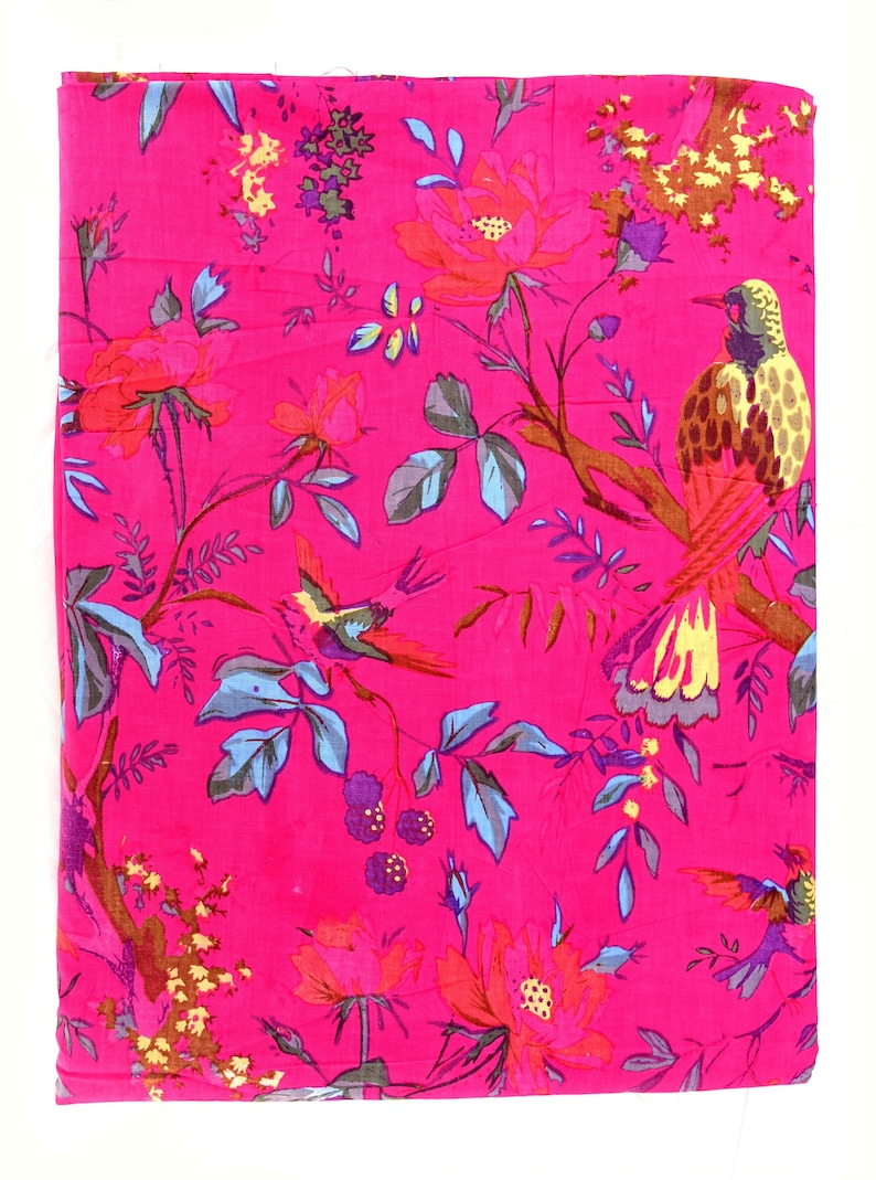 May include: Pink fabric with a floral and bird print. The fabric features a repeating pattern of pink, red, blue, yellow, and brown flowers, leaves, and birds.