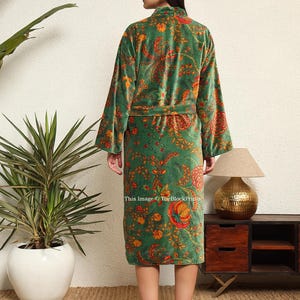 May include: A green velvet robe with a floral print. The robe has a tie belt and long sleeves.