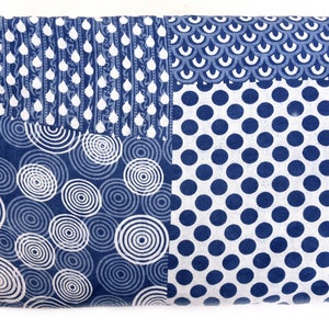 Op de afbeelding: Een blauwe en witte stof met een patchwork-ontwerp. De stof heeft vier verschillende patronen: cirkels, stippen, regendruppels en schubben.