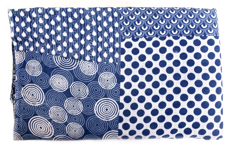 Op de afbeelding: Een blauwe en witte stof met een patchwork-ontwerp. De stof heeft vier verschillende patronen: cirkels, stippen, regendruppels en schubben.