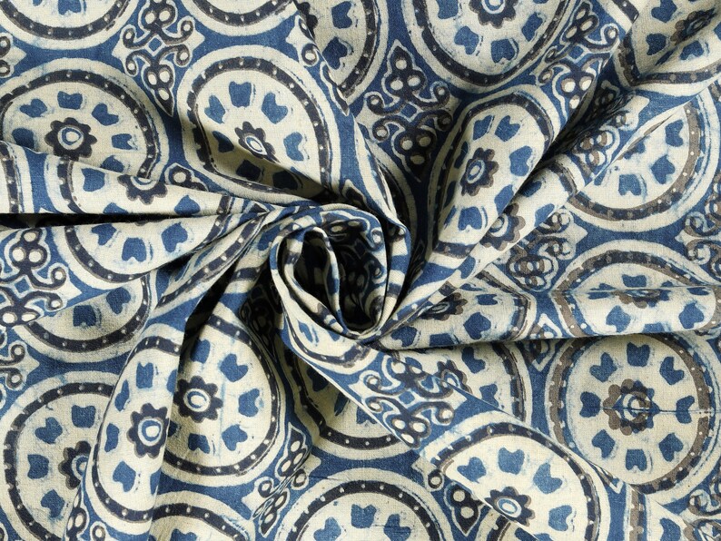 K&ouml;nnte beinhalten: Nahaufnahme eines blauen und wei&szlig;en Stoffes mit einem sich wiederholenden Muster aus kreisf&ouml;rmigen Designs. Der Stoff ist gefaltet und drapiert, wodurch die komplizierten Details des Musters sichtbar werden.