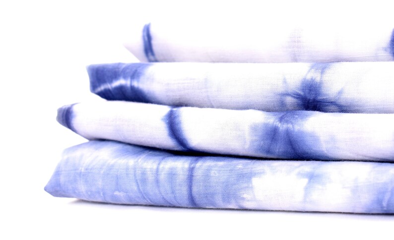 Peut inclure: Un empilement de quatre carr&eacute;s de tissu bleu et blanc en tie-dye.
