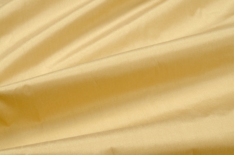 Puede incluir: Primer plano de una tela lisa de color amarillo p&aacute;lido con pliegues y arrugas suaves.