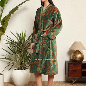 May include: A green velvet robe with a floral print and a self-tie belt. The robe has a long sleeve and a shawl collar.