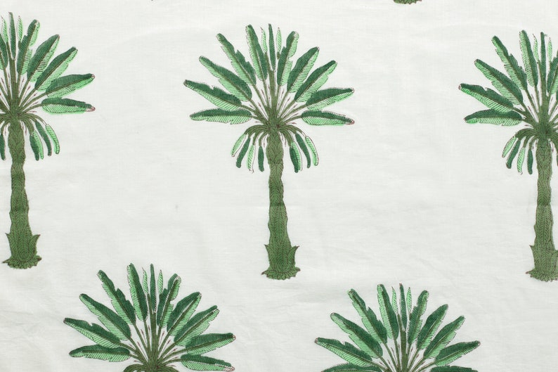 Peut inclure: Tissu blanc avec un motif r&eacute;p&eacute;t&eacute; de palmiers verts. Les palmiers ont un design stylis&eacute; avec un tronc central et des frondes rayonnant vers l'ext&eacute;rieur.