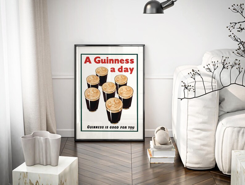 May include: Framed vintage Guinness advertisement featuring six pints of stout with creamy foam. The poster has red and white text that reads "A Guinness a day" and "Guinness is good for you."