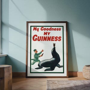 May include: A framed vintage Guinness advertisement. The poster features a seal balancing a pint of Guinness on its nose, with a man in a green uniform running towards it. The text "My Goodness My Guinness" is displayed in red and white.
