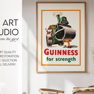 May include: A framed vintage Guinness advert. The poster shows a green steamroller with the word "GUINNESS" in red and "for strength" in green. The artwork is set against a cream background with an orange border. The frame is wooden.