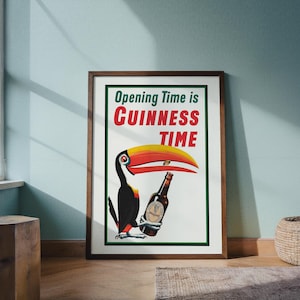 Puede incluir: P&oacute;ster vintage enmarcado de Guinness con un tuc&aacute;n sosteniendo una botella de cerveza Guinness. El p&oacute;ster tiene el texto "Opening Time is Guinness Time" en rojo y verde. El tuc&aacute;n tiene un gran pico amarillo y rojo.