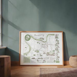May include: Framed vintage map print with a light wood frame. The map features a river, buildings, and illustrations in green and brown tones. The map has a circular emblem and text at the top and bottom.