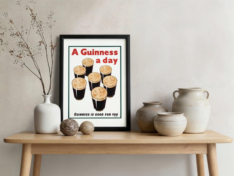 May include: Framed print featuring a vintage advertisement for Guinness. The artwork displays seven pints of Guinness with creamy foam, and the text "A Guinness a day" and "Guinness is good for you" in red and black.