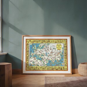 May include: A framed print of a historical map titled A Medieval Map of East and West, featuring a yellow border with illustrations of figures, a central map of Europe and Asia with blue oceans, and various small drawings of ships and people.