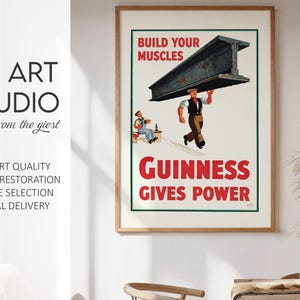 May include: A framed vintage Guinness advertisement print. The poster features a worker carrying a large steel beam with the text "BUILD YOUR MUSCLES" and "GUINNESS GIVES POWER" in red. The print is from KG ART STUDIO.