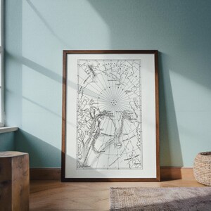 May include: A framed vintage map of the Arctic region, rendered in black and white. The map features detailed coastlines, geographical features, and directional lines. The frame is a dark brown wood, and the map is displayed on a light-colored background.